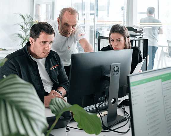 3 Mitarbeiter*Innen vor Computer in einer Besprechung