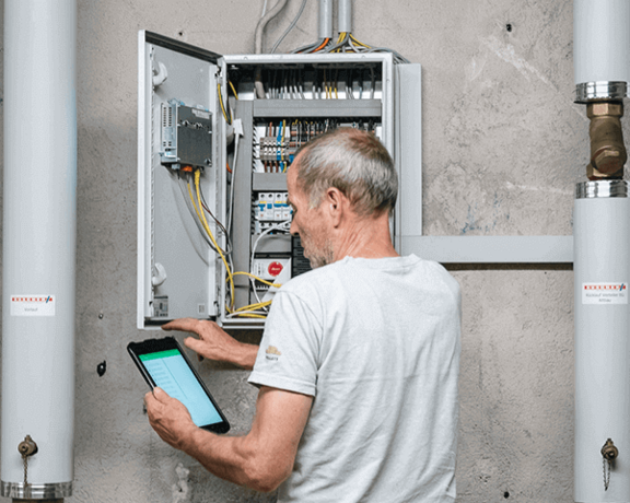 Heiztechniker im Sicherungskasten mit Tablett in Hand